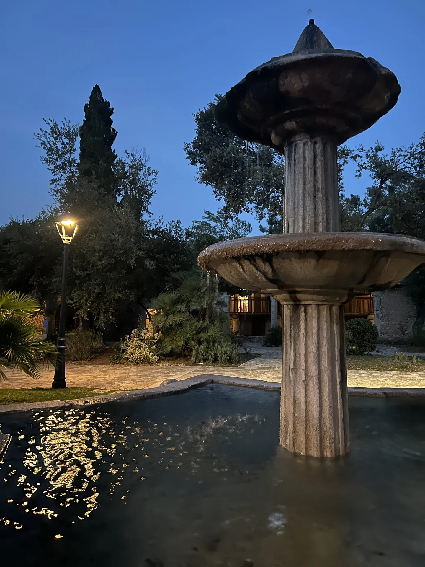 Steinbrunnen mit Wasserbecken im Klostergarten in der Abenddämmerung.