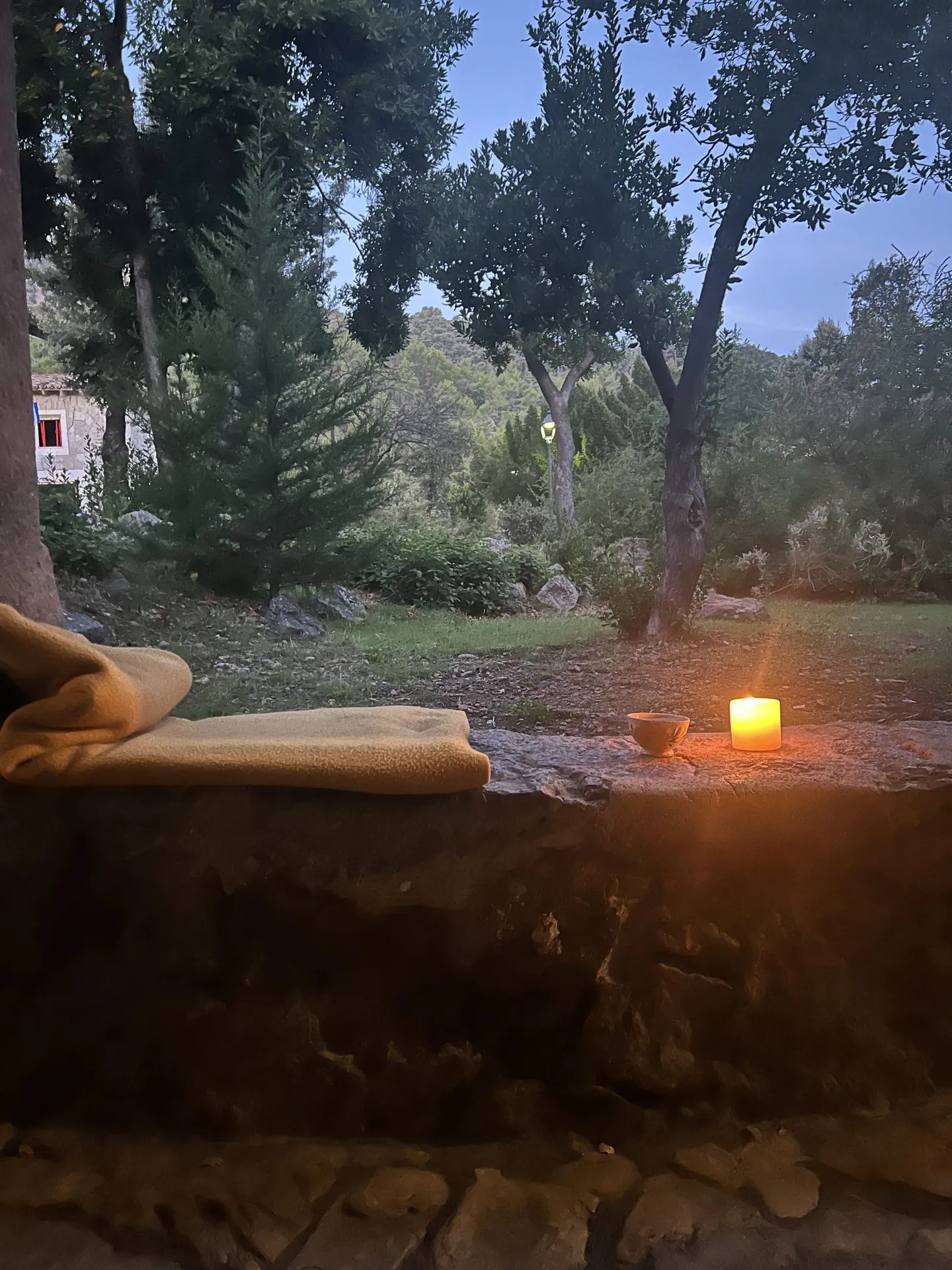 Steinbank mit Kerzen und Decken im warmen Abendlicht.