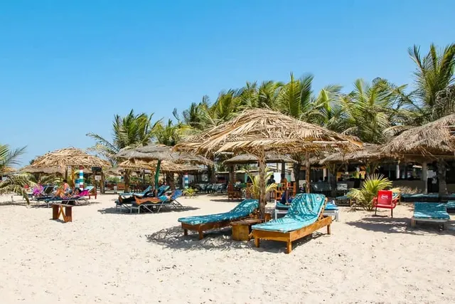 Strand mit Palmwedel-Sonnenschirmen und Liegen unter Palmen an der Smiling Coast